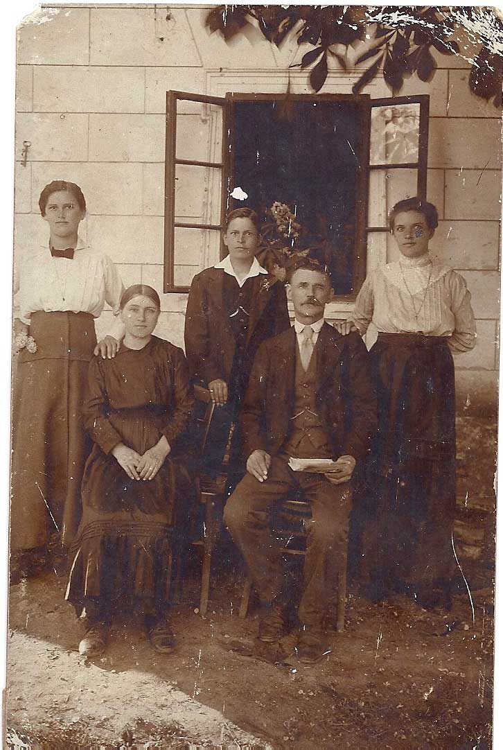 Sepia family photograph of five people in front of a house